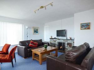 a living room with couches and a table and a tv at Godolphin in Wadebridge