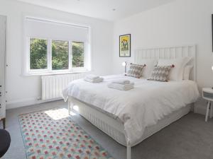 a white bedroom with a large bed and a window at 3 Church Hill House in Salcombe