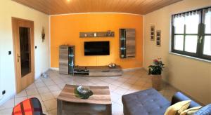 a living room with orange walls and a tv at Ferienwohnung Heymann in Hörnitz