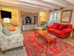 a living room with a red couch and a fireplace at Ros Vale in Penzance