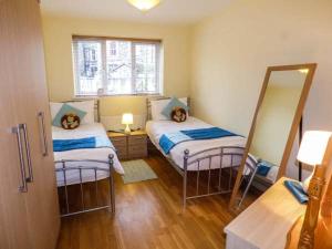 a small room with two beds and a mirror at Gwylanedd One in Llanfairfechan