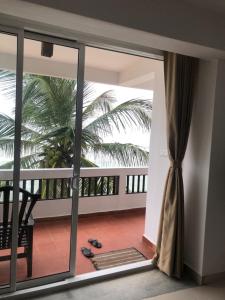 an open door to a balcony with a palm tree at La Veranda Di Serena in Unawatuna