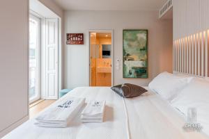 ON/SET Alfama - Lisbon Cinema Apartments في لشبونة: غرفة نوم بسرير ابيض عليها مناشف