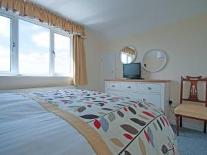 a bedroom with a bed and a tv and a window at Chynoweth in Crantock