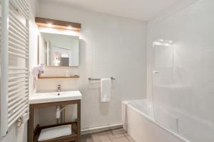 a white bathroom with a sink and a shower at Appart'City Confort Mulhouse in Mulhouse