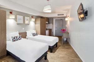 ミュルーズにあるAppart'City Confort Mulhouseのベッド2台とキッチンが備わるホテルルームです。