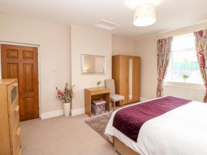 a bedroom with a bed and a desk and a window at Berrymoor Cottage in Brampton