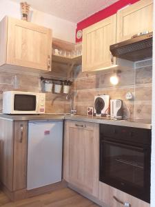 La cuisine est équipée de placards en bois, d'un four micro-ondes et d'un lave-vaisselle. dans l'établissement Le cocon, Centre station, à Les Deux Alpes