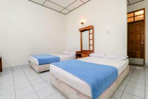 two beds in a room with white walls at Satriafi Hotel in Kaliurang