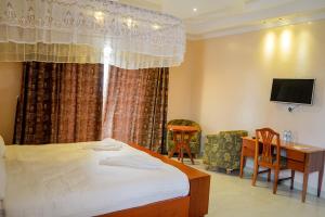 a bedroom with a bed and a desk and a television at Emmaus Guesthouse Kampala in Kampala