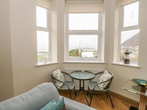 sala de estar con mesa, sillas y ventanas en Gwylanedd Two en Llanfairfechan