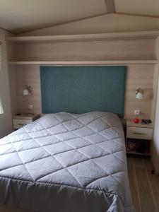 a bedroom with a large white bed with a blue headboard at Camping les dunes de contis in Saint-Julien-en-Born
