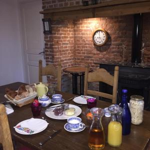 a dining room table with a clock on a brick wall at Chambre d'hote Frettecuisse in Frettecuisse