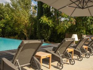 un grupo de sillas y una sombrilla junto a una piscina en Magnificent villa in the south of the Ard che, en Sallelles