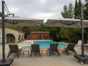 una piscina con 2 sombrillas y sillas, una mesa y una piscina en Magnificent villa in the south of the Ard che, en Sallelles