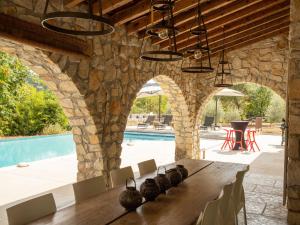 un comedor con paredes de piedra, mesa y piscina en Magnificent villa in the south of the Ard che, en Sallelles