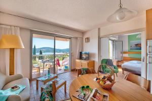 una sala de estar con mesa y una habitación con vistas. en Village Club Les Mas de L'Esterel, en Agay - Saint Raphael