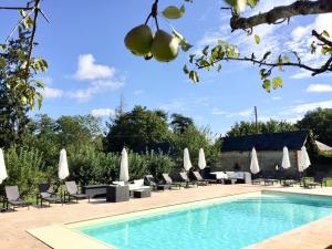 a pool with chairs and umbrellas next to a resort at Domaine de la Haute-Porte in Souvigné-sur-Sarthe