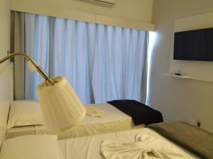 a hotel room with two beds and a lamp at Florinn Praia Hotel in Florianópolis