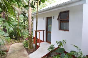 a white house with a pathway leading to the door at Cashew Nut Grove Chalets in Port Glaud