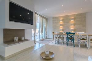 een woonkamer met een tv en een tafel met stoelen bij Villa Niraclò by Raro Villas in Carovigno
