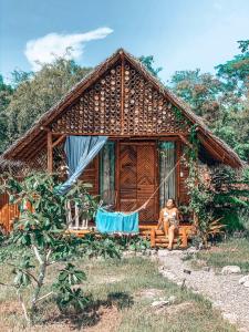 a woman sitting on the porch of a house at Tongo Hill Cottages in Moalboal