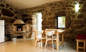 een keuken met een tafel en stoelen en een stenen muur bij Casa de Vila Cete in Alpendurada