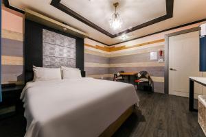 um quarto com uma grande cama branca num quarto em Manhattan Hotel em Cheongju