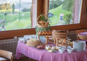 una mesa con pan y bollería en una mesa con ventana en Restaurant und Kaeserei Berghof en Ganterschwil