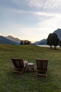dwa krzesła i stół na polu z górami w obiekcie Hotel Bellavista w mieście Silvaplana