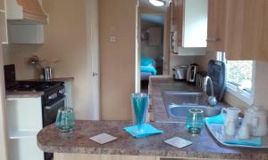 een keuken met een wastafel en een aanrecht met glazen erop bij Sunspot Brixham in Brixham