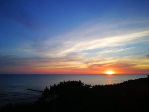 un tramonto sull'oceano con il sole nel cielo di Porta Mare Apartments LuxView a Dziwnówek