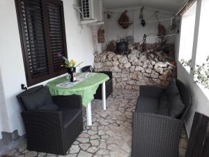 a patio with a table and chairs and a stone wall at Apartments Lidija in Pag