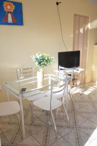 uma mesa de jantar com cadeiras brancas e uma televisão em Casa na Praia de Barra do Gil em Vera Cruz de Itaparica