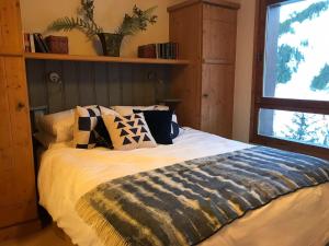 a bedroom with a bed with pillows and a window at Arc 1950 Apartment - Sources de Marie, Mountain View in Arc 1950 +16 photos