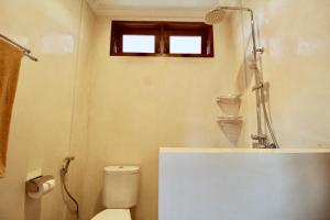 uma casa de banho com um WC, um chuveiro e uma janela. em Pacha House em Ubud