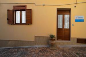 un edificio con due finestre e una porta e una pianta in vaso di Casa Vacanze Meraki a Noto