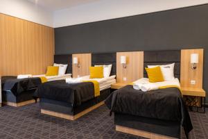 a room with three beds with yellow pillows at Hotel Nad Czernicą in Czarne