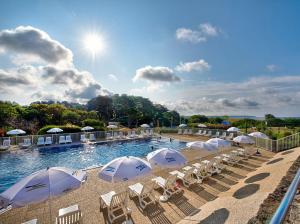 a swimming pool with white umbrellas and chairs at Village Club Kerlannic in Arzon