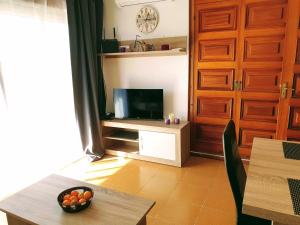 uma sala de estar com uma televisão e uma mesa em Puerto Simona 11A em Roses