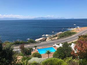 a road with a swimming pool next to the ocean at Rocklands Seaside Bed and Breakfast in Simonʼs Town