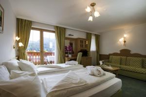 a hotel room with two beds and a couch at Hotel Casa del Campo in Madonna di Campiglio