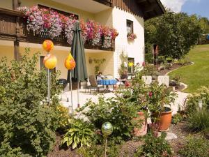 einen Garten mit Sonnenschirm und Menschen am Tisch in der Unterkunft Ferienhaus Weps in Arnbruck