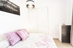 a white bedroom with a bed with purple pillows at Calpe Beach in Calpe