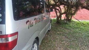 a silver van parked in the grass next to a tree at White Castle Hotel Arua in Gulu