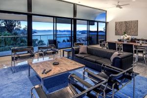 een woonkamer met een bank en tafels en stoelen bij Waves 3 Luxury 3 Bedroom Endless Ocean Views Central Location + Buggy in Hamilton Island
