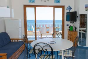 een woonkamer met een tafel en stoelen en de oceaan bij Beach House Acquamarina in Letojanni