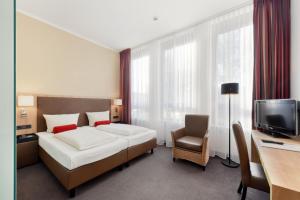 a bedroom with a bed and a desk and a television at ACHAT Hotel München Süd in Munich