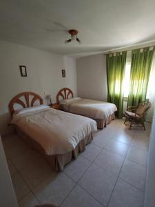 a hotel room with two beds and a chair at Apartamentos Rascafria Cerquilla in Rascafría