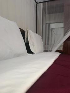 a close up of a bed with white sheets and pillows at Le Parlour in Boma la Ngombe